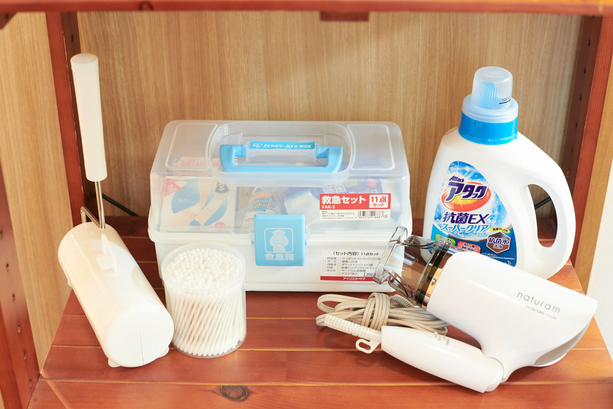 A storage box with various cleaning supplies, a bottle of disinfectant, a hairdryer, and a set of keys.