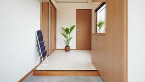 A hallway with wooden flooring, a potted plant, and a chair rack. - Ryoushi Minpaku CHOUTA (Awaji)