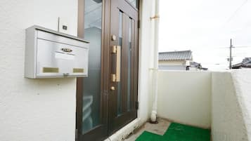 A narrow entrance with a dark wooden door, a mailbox, and a small green mat.