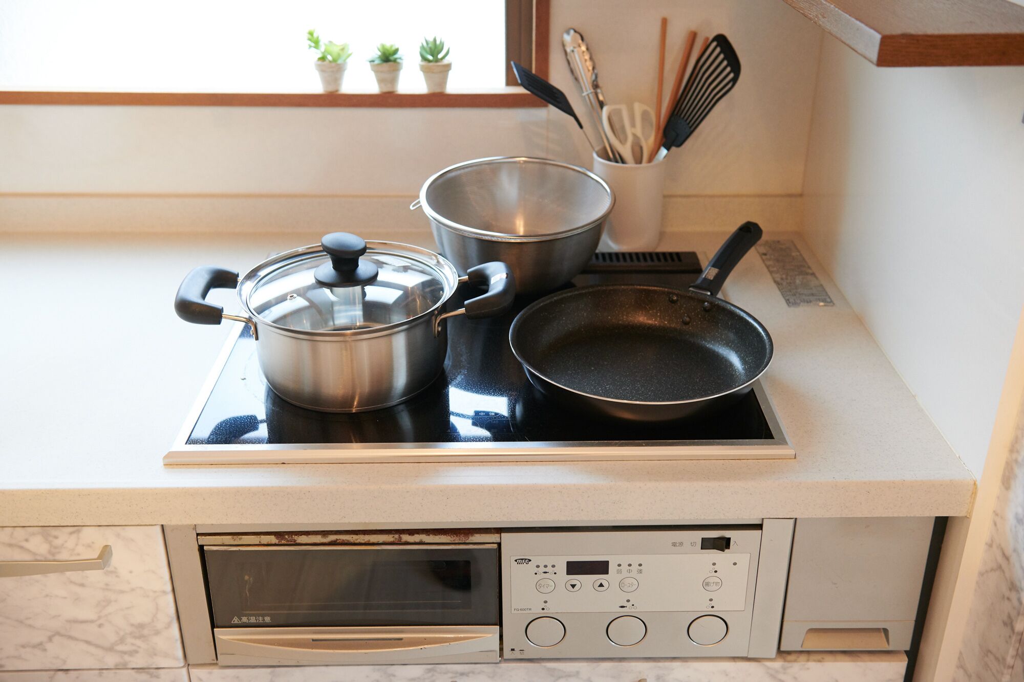 Una cocina con estufa, ollas y una sartén.