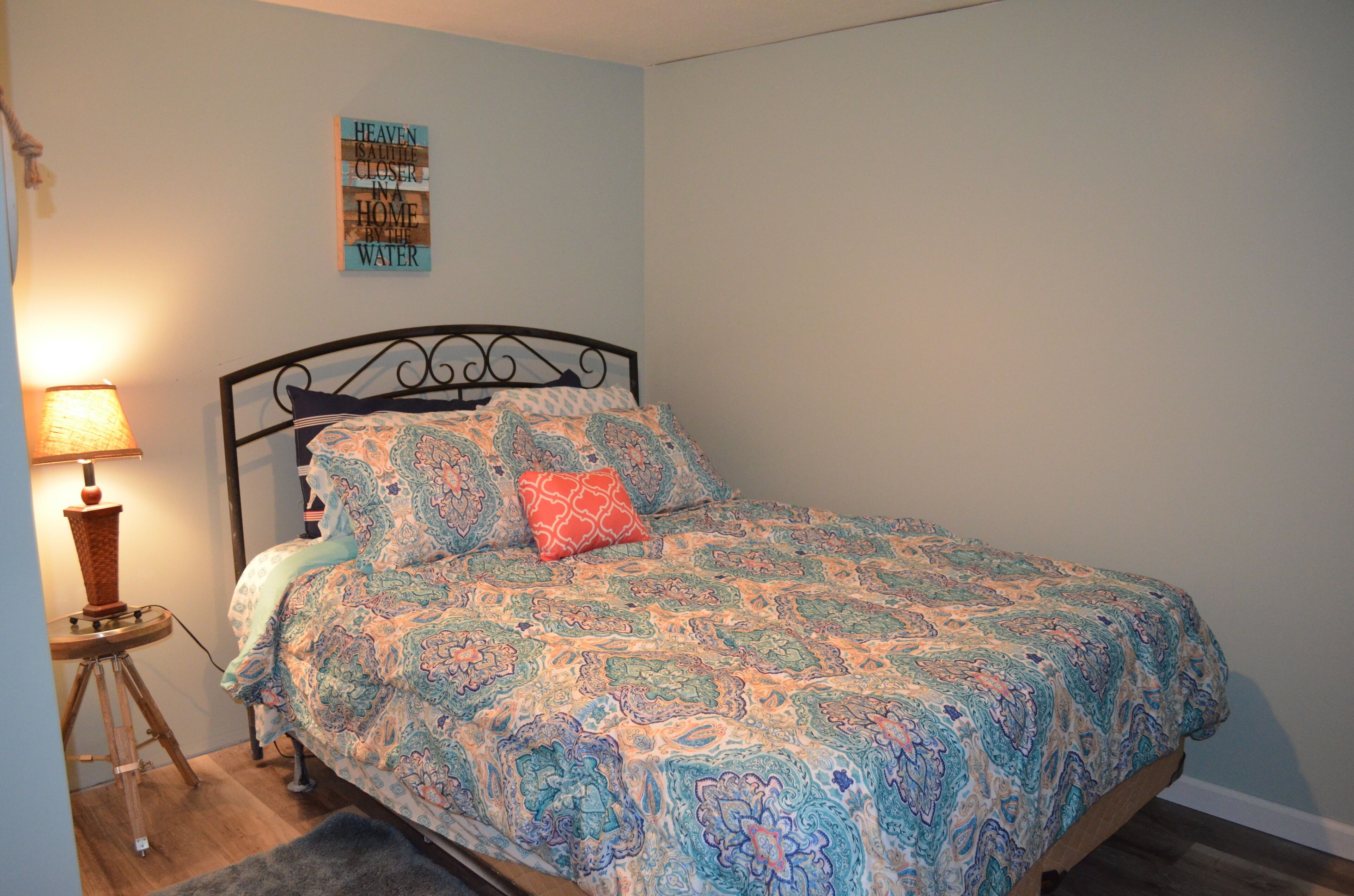 Ein Schlafzimmer mit Bett, Nachttisch, Lampe und Wandbild.
