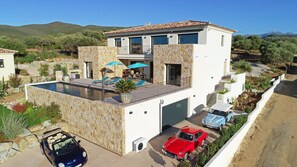 Enjoy a rooftop infinity pool with a cabana and outdoor seating area offering a view of the surrounding hills.
