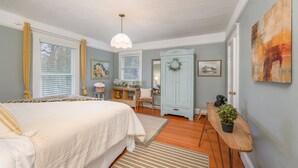 A bedroom with a large bed, a desk, a wardrobe, and a door with a wreath. - Beautiful Wine Country Escape (Carlton)