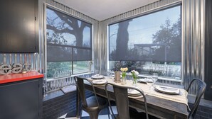 A modern kitchen with large windows, a dining table set for four, and a red countertop. - Beautiful Wine Country Escape (Carlton)