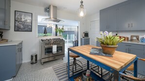 A modern kitchen with a gas stove, stainless steel appliances, a wooden table, and a hanging light fixture. - Beautiful Wine Country Escape (Carlton)