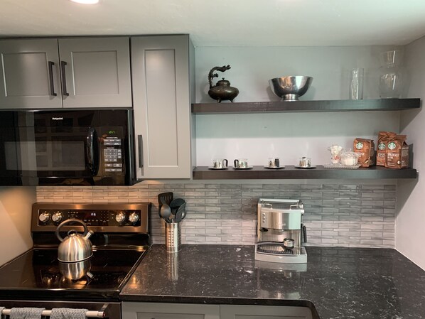 Una cocina moderna con microondas, estufa y cafetera.