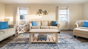 Ein Wohnzimmer mit einem beigefarbenen Sofa, zwei Sesseln, einem Couchtisch aus Holz und einem gemusterten Teppich.