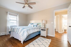 A bedroom with a bed, nightstand, lamp, ceiling fan, and a view of the hallway. - Spacious Home Ready for your memories(2 blocks to beach, downtown and train) (Point Pleasant Beach)