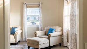 Ein Zimmer mit zwei Sesseln, einem fensterbelaubten Fenster und Holzboden.