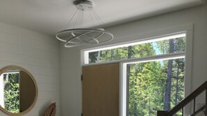 Un interior moderno con un banco de madera, un espejo redondo, una puerta de madera y una escalera.