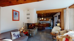 Una sala de estar acogedora con chimenea, un sofá, una mesa de comedor y una cocina al fondo.