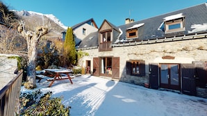 Un edificio de piedra con un muelle de madera y un patio cubierto de nieve.