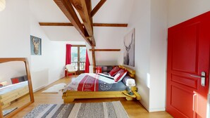 Un dormitorio con una cama de madera, una puerta roja y vistas al exterior.