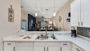 Una cocina moderna con una isla central, pileta doble e iluminación colgante.