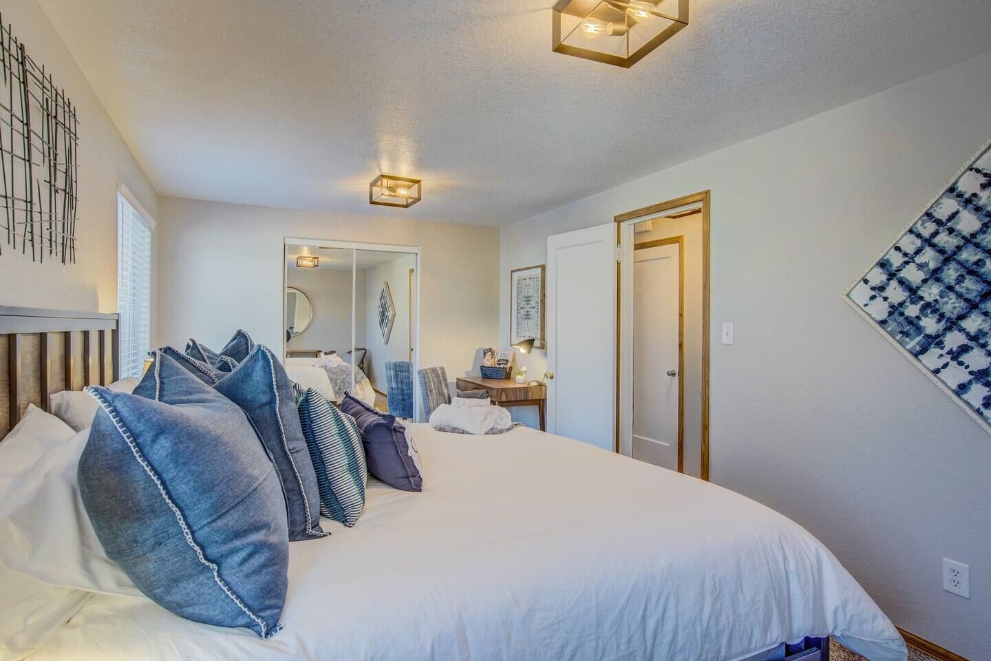 A bedroom with a large bed, a bedside table, a mirror, and a wardrobe.