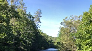 A wooden bridge over a river surrounded by dense greenery. - Private pet-friendly Aska Adventure Area getaway with gorgeous views! (Blue Ridge)