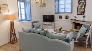 A living room with a sofa, chairs, a TV, and a fireplace. - Hydra's Pearl - Blue Pearl (Hydra)