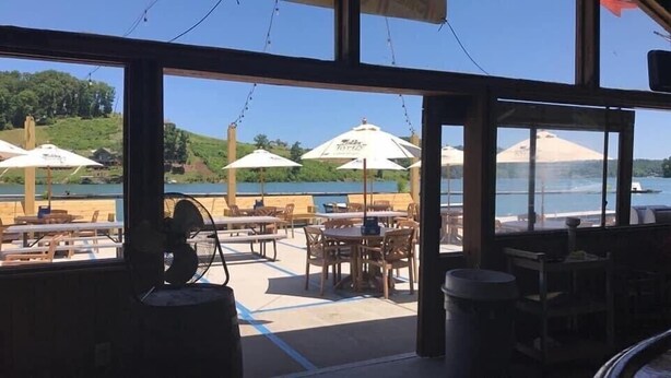 Un espace de restauration en plein air avec des tables et des chaises, des parasols et une vue sur l’eau.