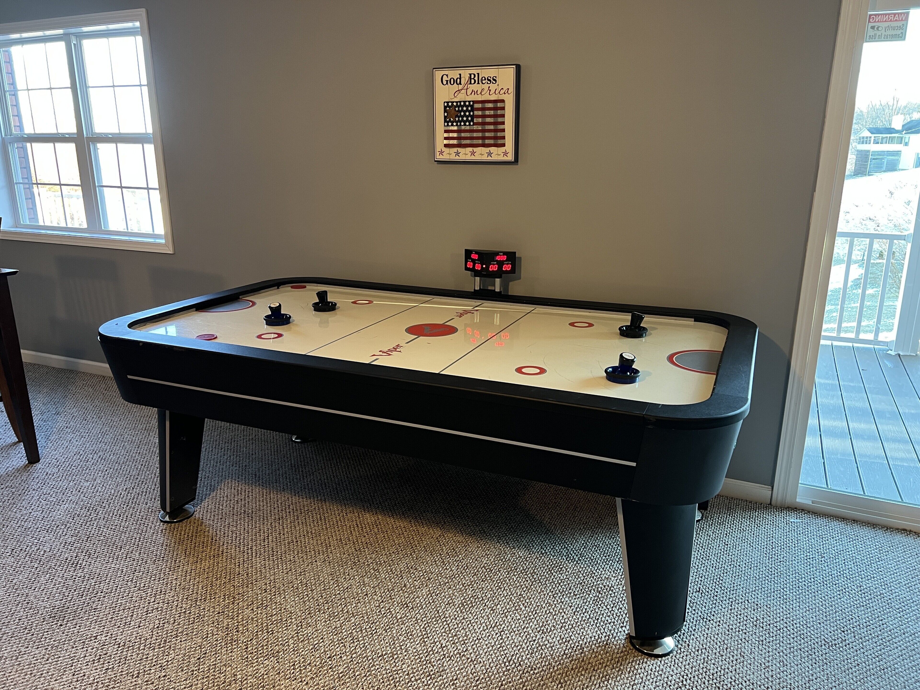 A foosball table in a room with a window and a framed American flag.
