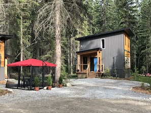 Situated in a forested area, this cabin-style building features a porch, deck, and well-maintained lawn.