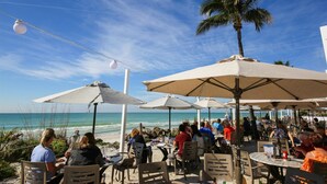 Un espace extérieur aménagé avec des tables et des parasols, offrant une vue sur l’océan.