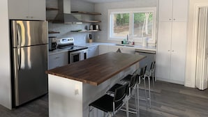 Una cocina moderna con electrodomésticos de acero inoxidable, una isla de madera y un ventanal con vistas al exterior.