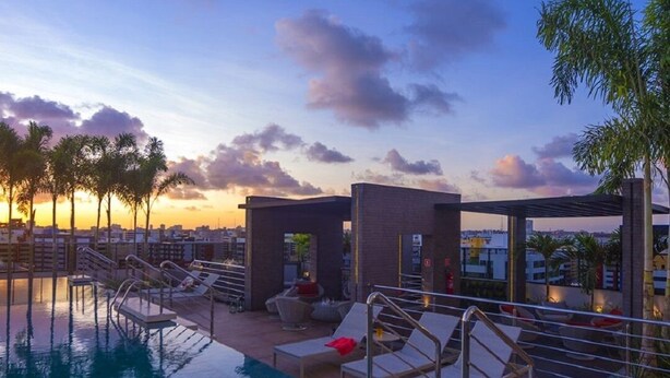 A rooftop pool area with lounge chairs and a small building, likely a spa or sauna, under a sunset sky. - TIME BUILDING - BEST LOCATION IN THE CITY (maceio)