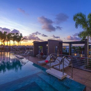 A rooftop pool area with lounge chairs and a small building, likely a spa or sauna, under a sunset sky. - TIME BUILDING - THE BEST LOCATION IN TOWN (maceio)