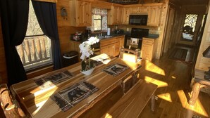 A wooden cabin interior with a dining table, kitchen area, and a loft space. - Spectacular Mountain View is Yours to Enjoy (Sevierville)