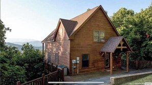 A wooden cabin with a pitched roof, a porch, and a view of the surrounding forest. - Spectacular Mountain View is Yours to Enjoy (Sevierville)