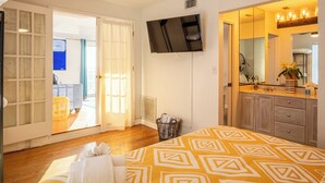 A bedroom with a bed, a TV, a mirror, and a sliding door leading to a balcony. - SURFS UP - UP STAIRS UNIT (Bradenton Beach)