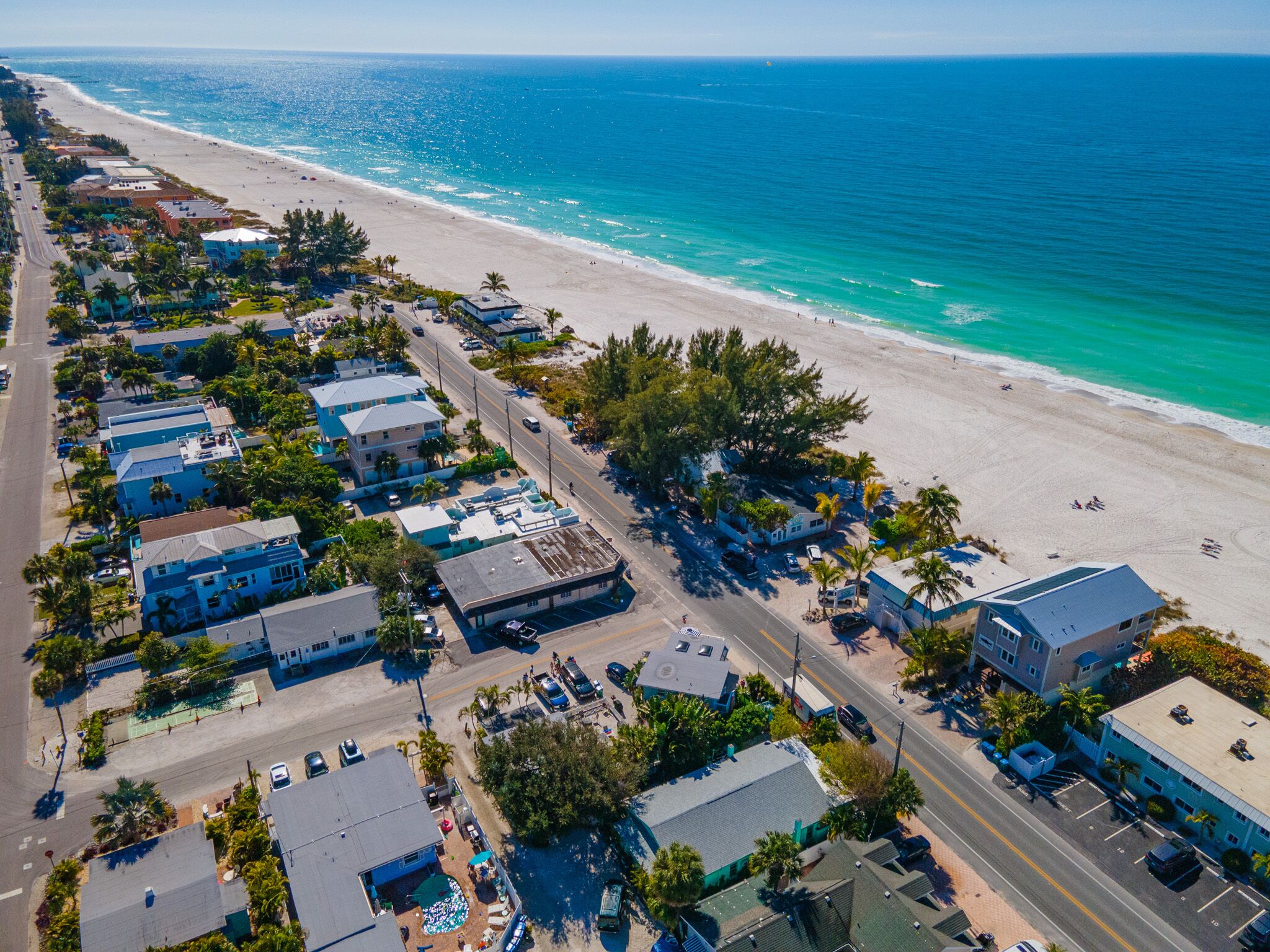 An aerial view of a coastal town with beachfront properties, roads, and a beach.