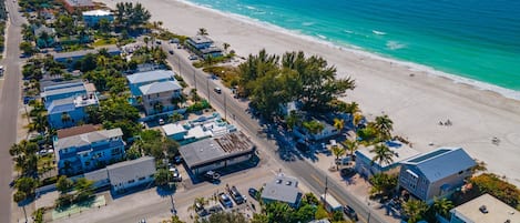 An aerial view of a coastal town with beachfront properties, roads, and a beach.