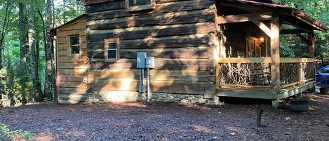 Une cabane rustique avec des fondations en pierre, un revêtement extérieur en bois et une véranda.