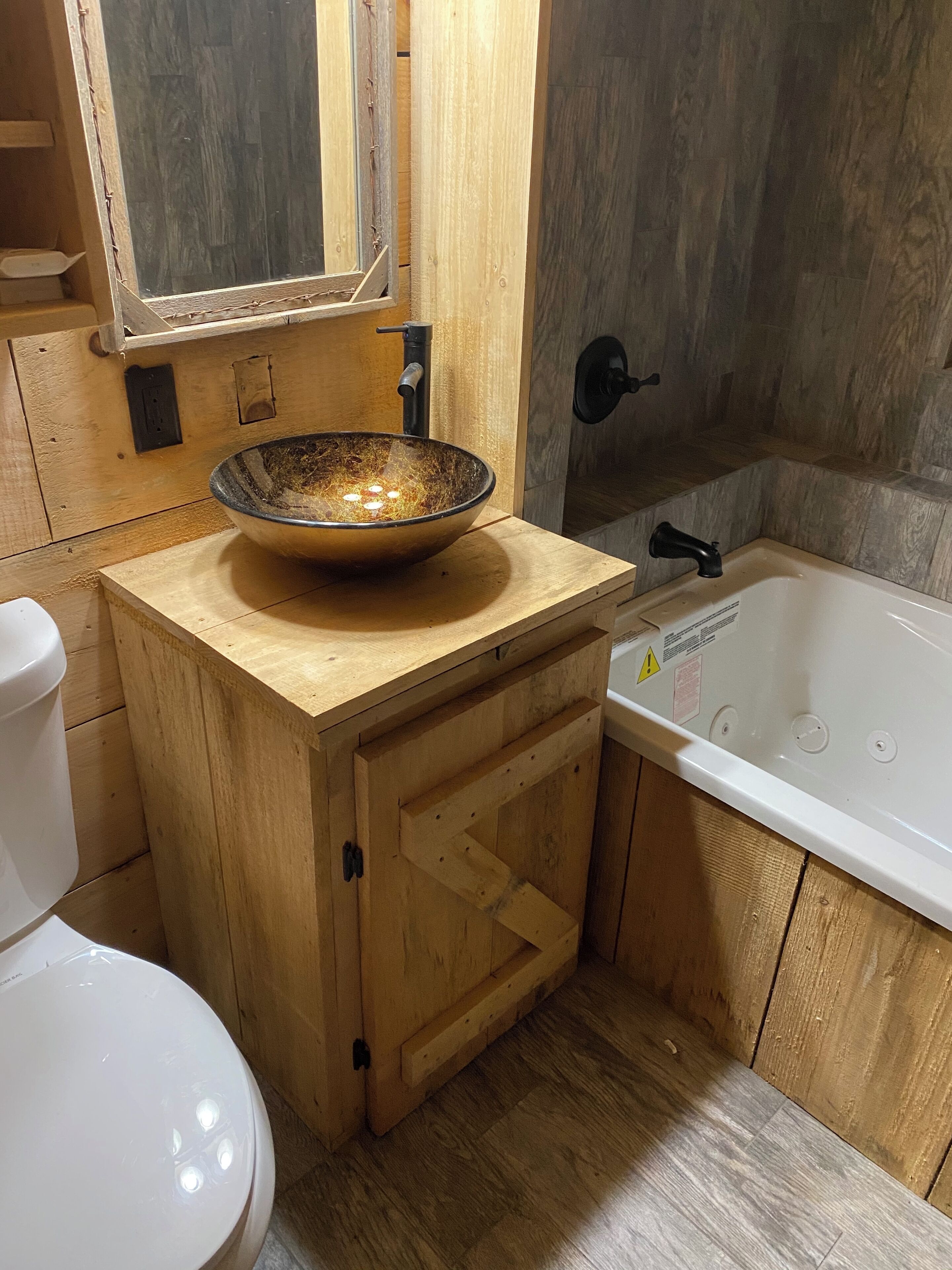 A wooden vanity with a bowl sink, a toilet, and a bathtub.