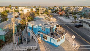 A coastal residential area with a prominent blue house featuring a balcony and a small outdoor seating area. - Low Rider - Bottom Unit -  (Bradenton Beach)