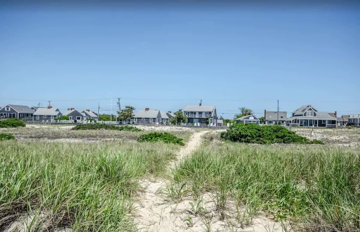 Un quartier résidentiel situé sur la côte, avec des maisons et un sentier de sable.