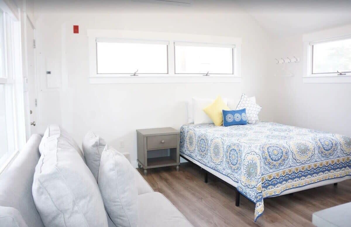 Une chambre à coucher avec un lit, une table de chevet, une fenêtre et un canapé.