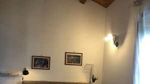 Una camera da letto con un letto, due luci a parete e due quadri appesi.