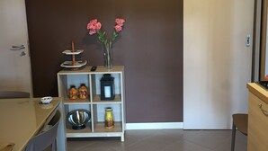 Un'area pranzo con tavolo e sedie, una mensola con oggetti decorativi e una porta.