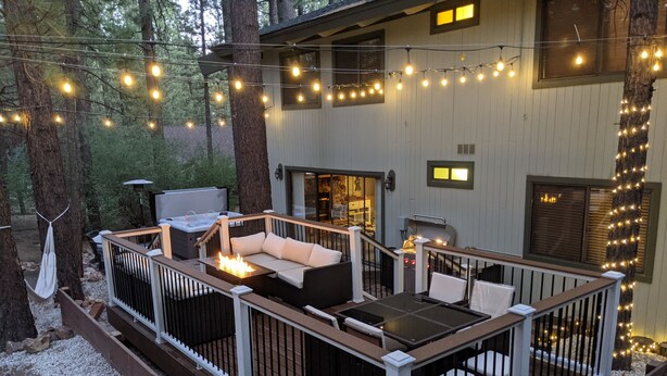 An outdoor deck with a fire pit, seating, and string lights.