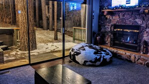 A cozy living room with a stone fireplace, a glass door leading outside, and a comfortable seating area.