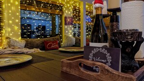 A cozy room with a wooden table, a bottle of wine, a candle, and a bear figurine.