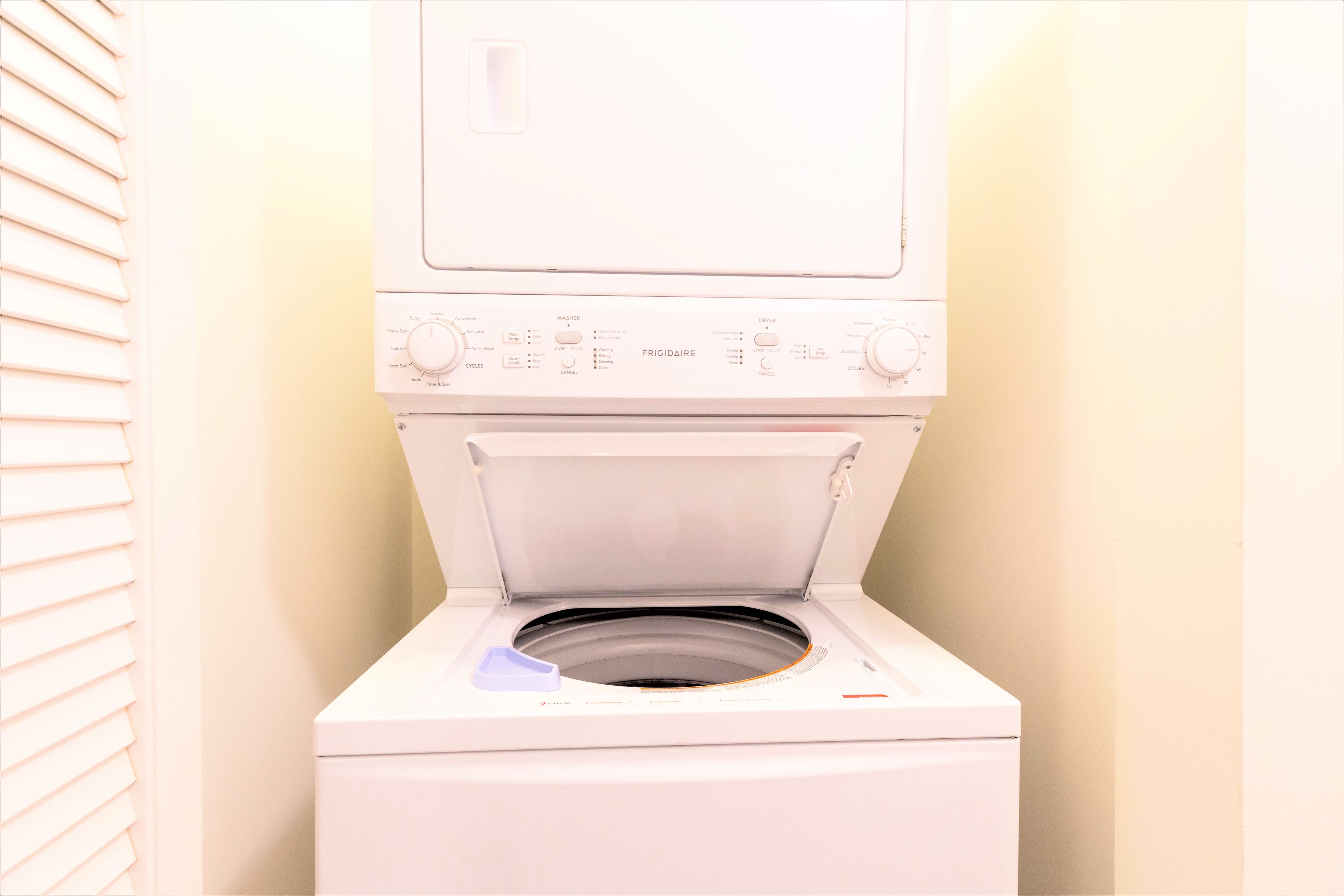 A front view of a white washing machine with control panel, open door, and a blue detergent dispenser.