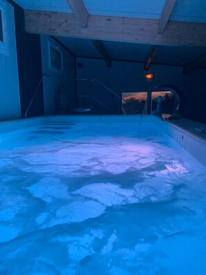An indoor swimming pool with a blue-lit floor, wooden beams, and a ladder leading to a door. - Belle Villa 2h private relaxation area included in nightly rate (Équilly)