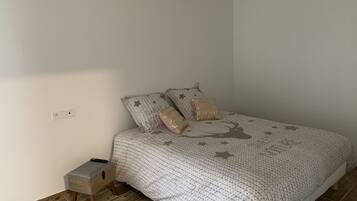 A bedroom with a bed, a nightstand, and a power outlet on the wall.