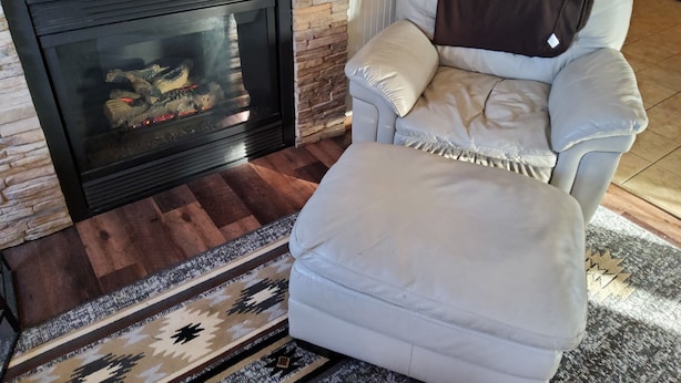 Un salon moderne avec une cheminée en pierre, un canapé en cuir blanc et un tapis à motifs.