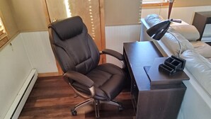 Un fauteuil de bureau moderne sur roulettes, un bureau et une lampe.