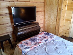 Ein Zimmer mit einem Bett, einem Holzschrank und einem Fernseher darauf.