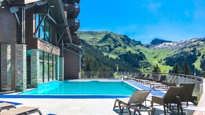 A pool area with lounge chairs and a view of mountains.